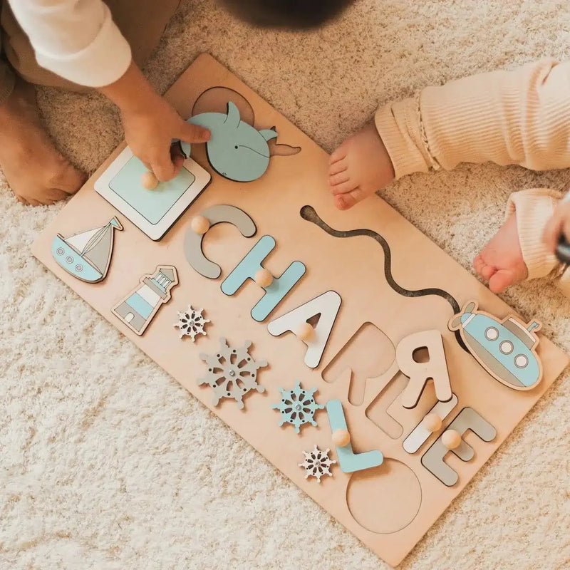 Deux enfants jouent sur un tapis beige avec le Puzzle Personnalisé Prénom en Bois, personnalisé avec "Charlie" et des pièces amusantes sur le thème nautique.
