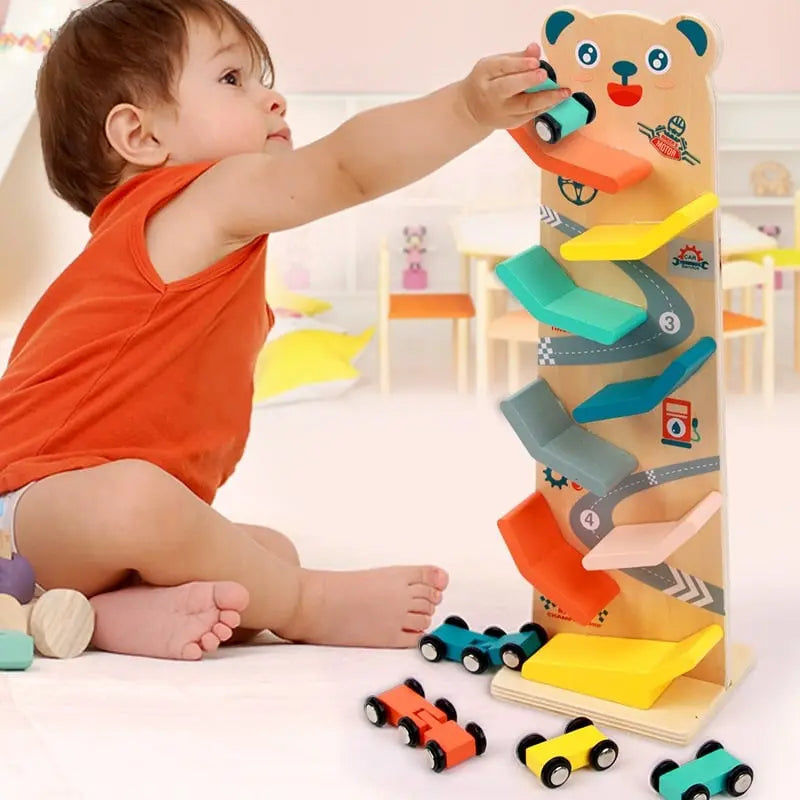 Un tout-petit joue avec une Rampe en Bois Votures - Piste de Course pour Tout-Petits, en utilisant la rampe pour faire la course de petites voitures.