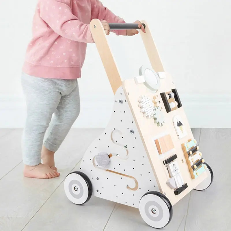 Une petite fille joue avec un Trotteur pousseur bébé - multi-activités - Couleurs pastel.