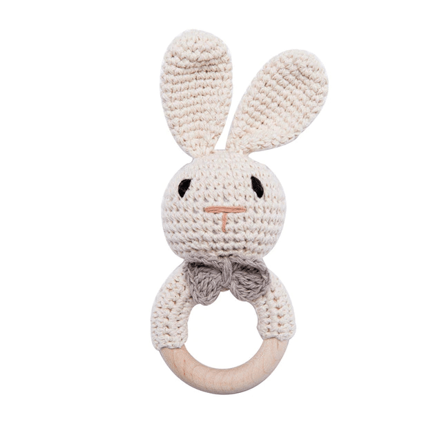 L'Anneaux de dentition Animaux – bois et crochet est un hochet lapin crocheté avec de longues oreilles, une poignée en anneau en bois et un nœud gris, parfait pour les petits.
