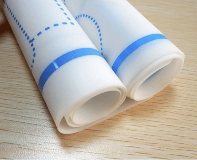 Une jolie configuration minimaliste mettant en scène le « Set de table montessori » : deux draps blancs enroulés avec des lignes bleues sur une surface en bois, évoquant une ambiance Montessori.