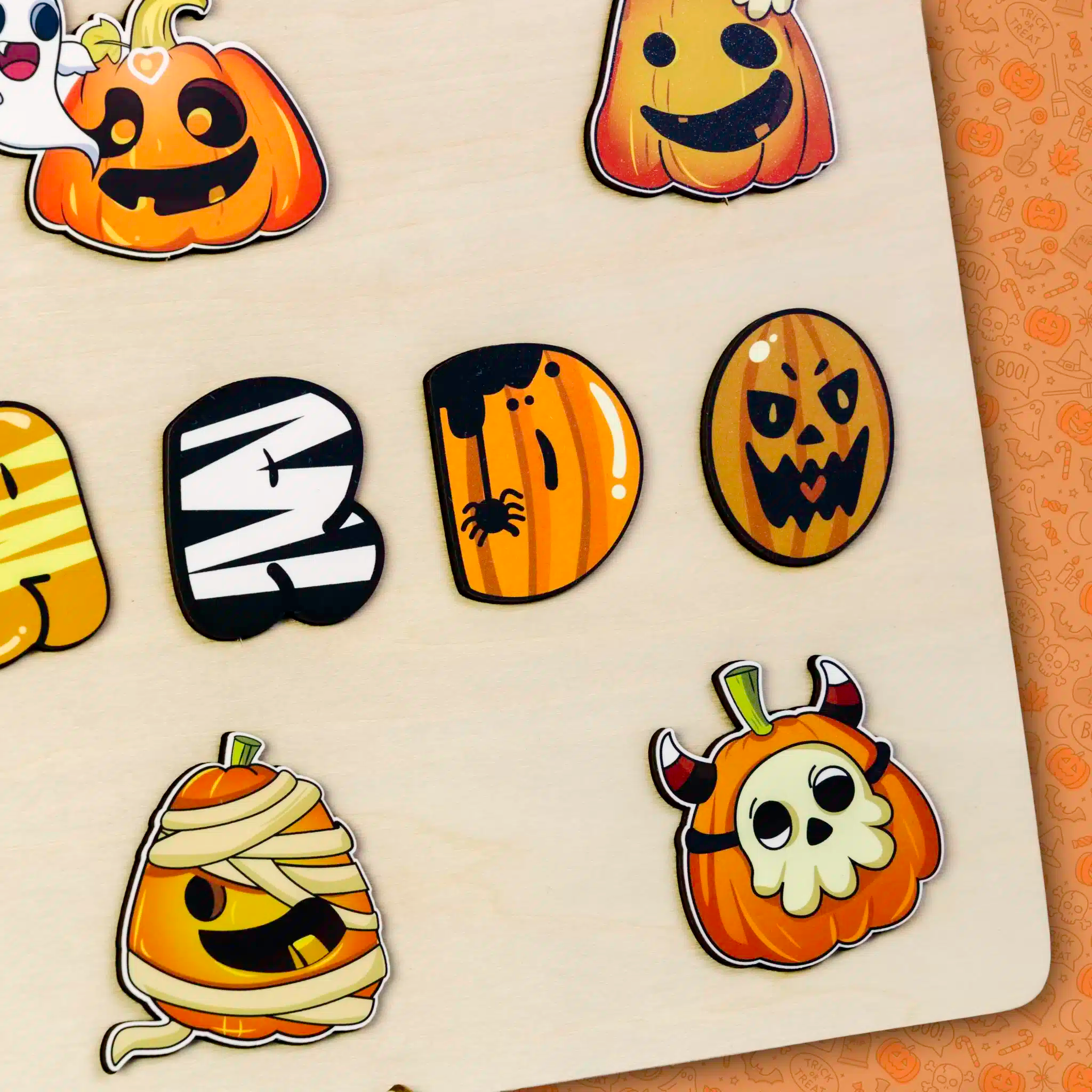 Feuille d'autocollants décorée de visages de citrouilles de dessins animés sur le thème d'Halloween, y compris des momies, des fantômes et des crânes, disposés sur une surface en bois rustique - un souvenir parfait particulièrement adapté à la saison.