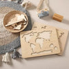 Le « Puzzle du monde en bois Montessori » repose sur un tapis à pompons texturé, avec un petit panier, un appareil photo jouet et des blocs de bois étiquetés « Halloween » et « Pâques », capturant l'essence tactile de l'apprentissage Montessori.