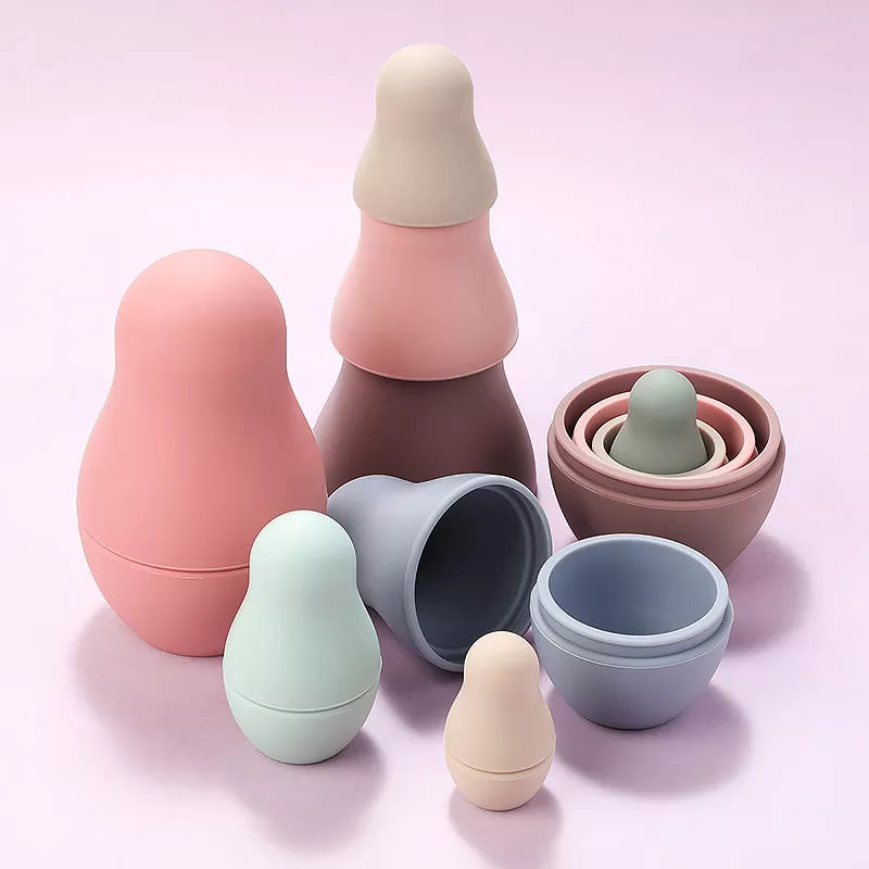 Un groupe de récipients en plastique de différentes couleurs sur fond rose.
