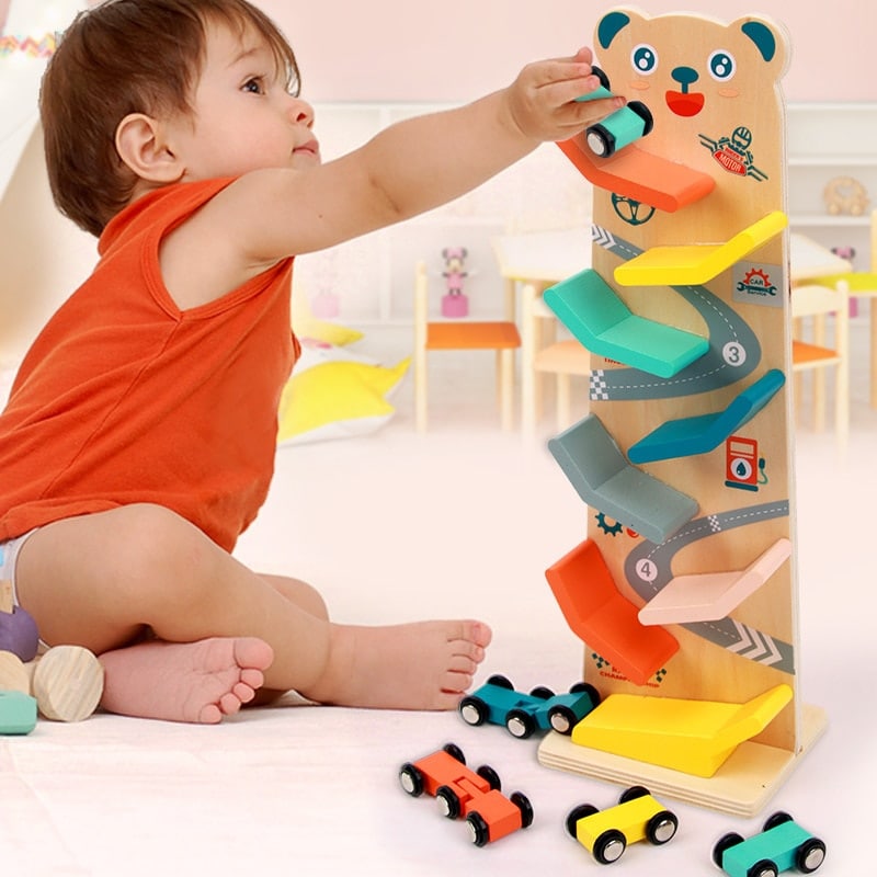 Un tout-petit joue avec une Rampe en Bois Votures - Piste de Course pour Tout-Petits, en utilisant la rampe pour faire la course de petites voitures.