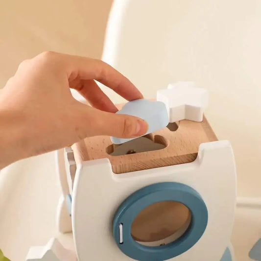 Une personne met un jouet dans une boîte en bois.