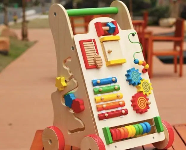 Un Chariot de Marche Bébé - Coloré vibrant sur une table en bois.