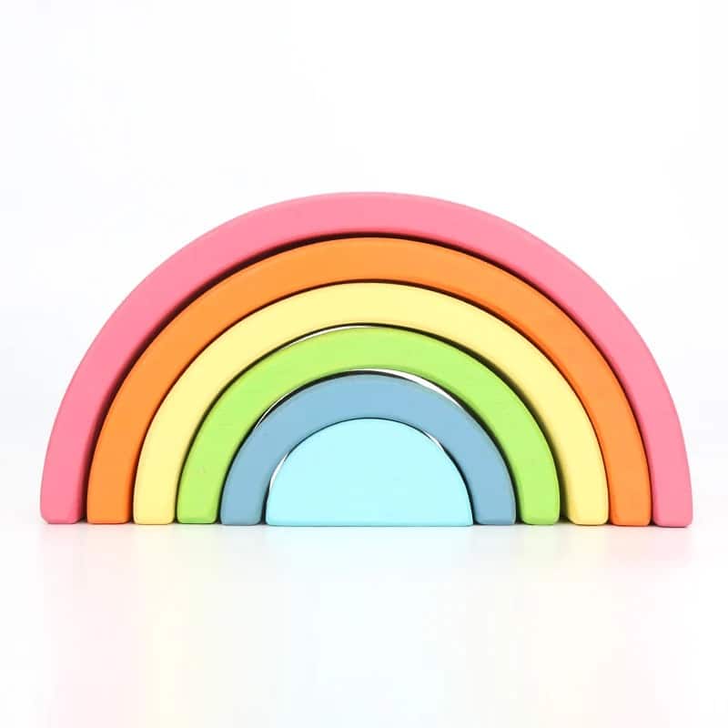Arc-en-ciel en bois coloré empilé par ordre de taille sur un fond blanc.