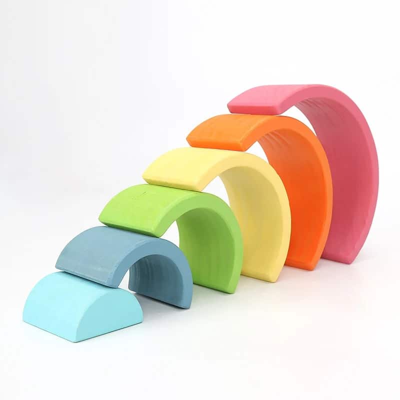 L'Arc-en-ciel en bois coloré est disposé en demi-cercle sur un fond blanc.