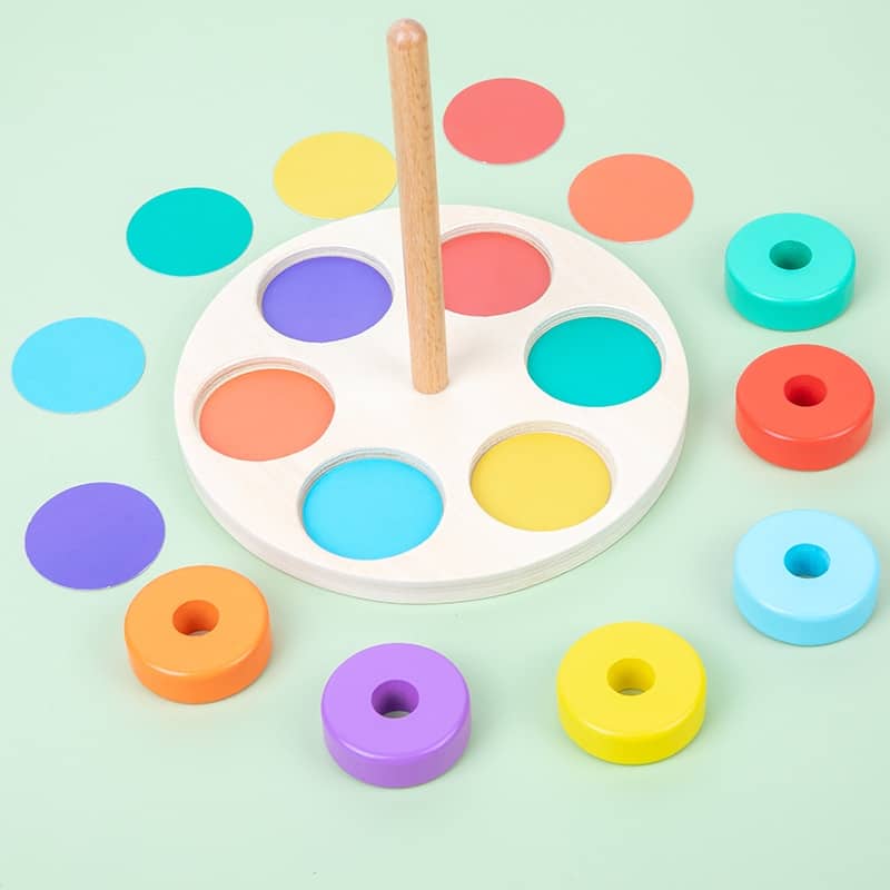 Un jeu de cercles à enfiler en bois avec des cercles colorés et un bâton en bois.