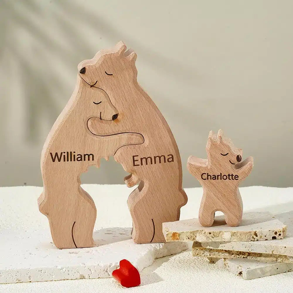 Les figurines Puzzle Personnalisé De Famille D'ours En Bois, mettant en vedette les personnages William, Emma et Charlotte, sont disposées sur une surface texturée avec un petit cœur rouge placé à proximité.