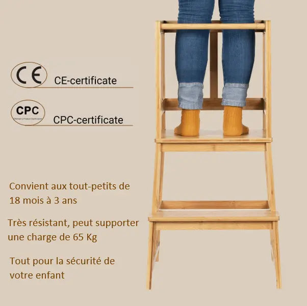 Une personne se tient debout sur un marchepied en bois certifié CE et CPC appelé Tour d’observation Montessori. Il supporte jusqu’à 65 kg et convient aux enfants âgés de 18 mois à 3 ans, comme le souligne le texte en français.