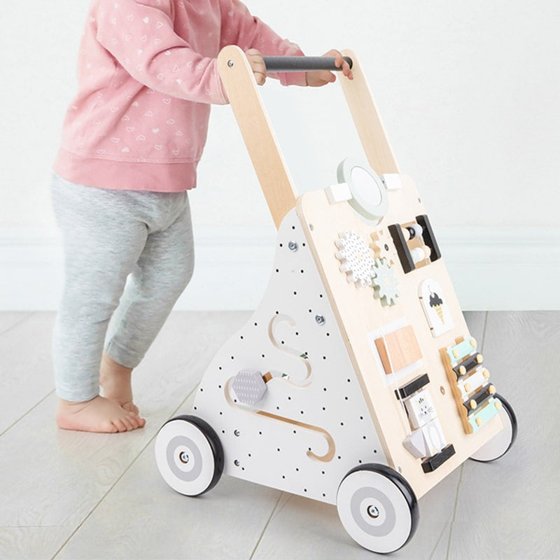Une petite fille joue avec un Trotteur pousseur bébé - multi-activités - Couleurs pastel.